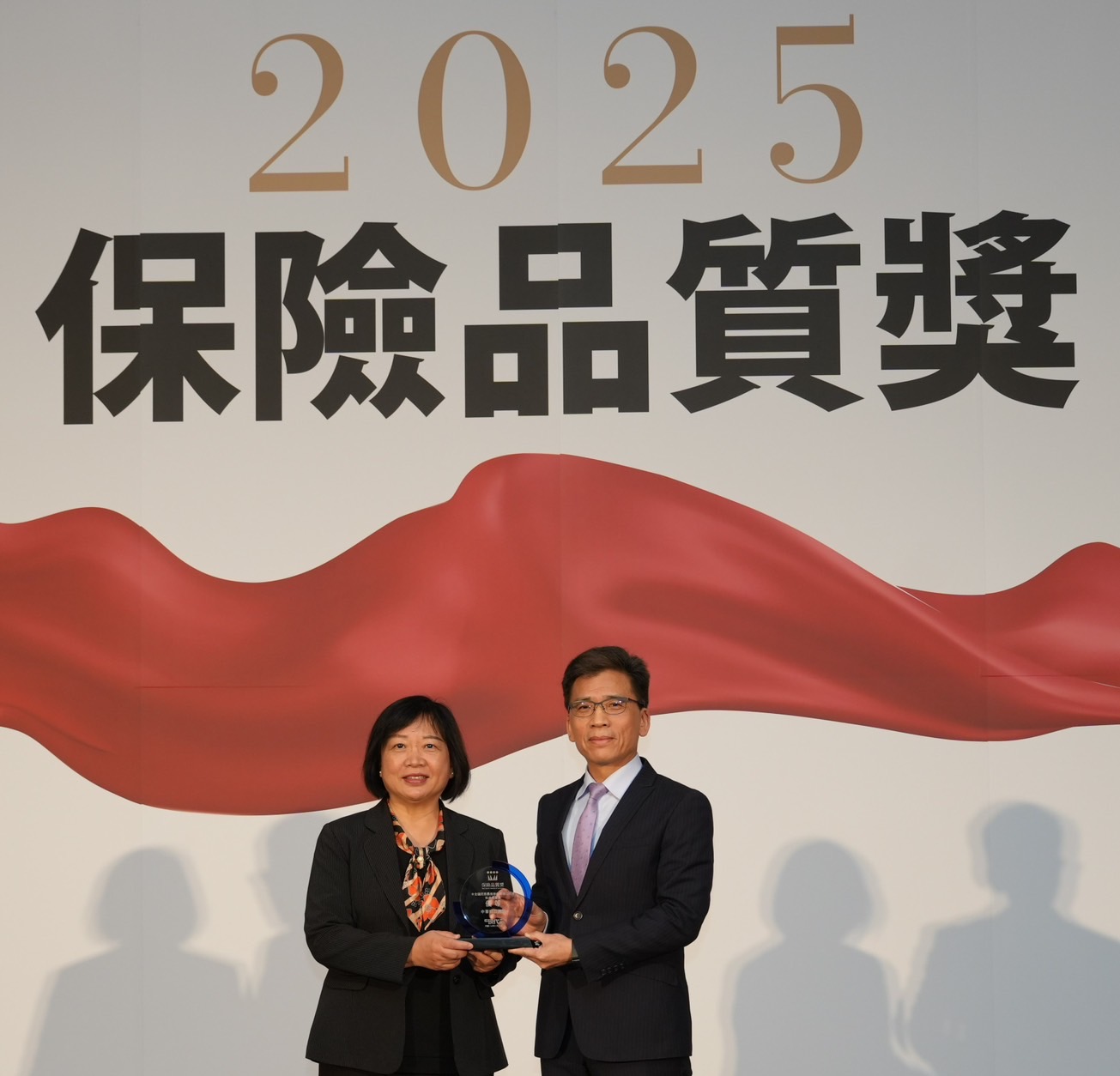 中華郵政榮獲「2025保險品質獎」2項優等殊榮，由協理簡詠涵(左)代表出席，接受金管會主委彭金隆(右)頒獎。
